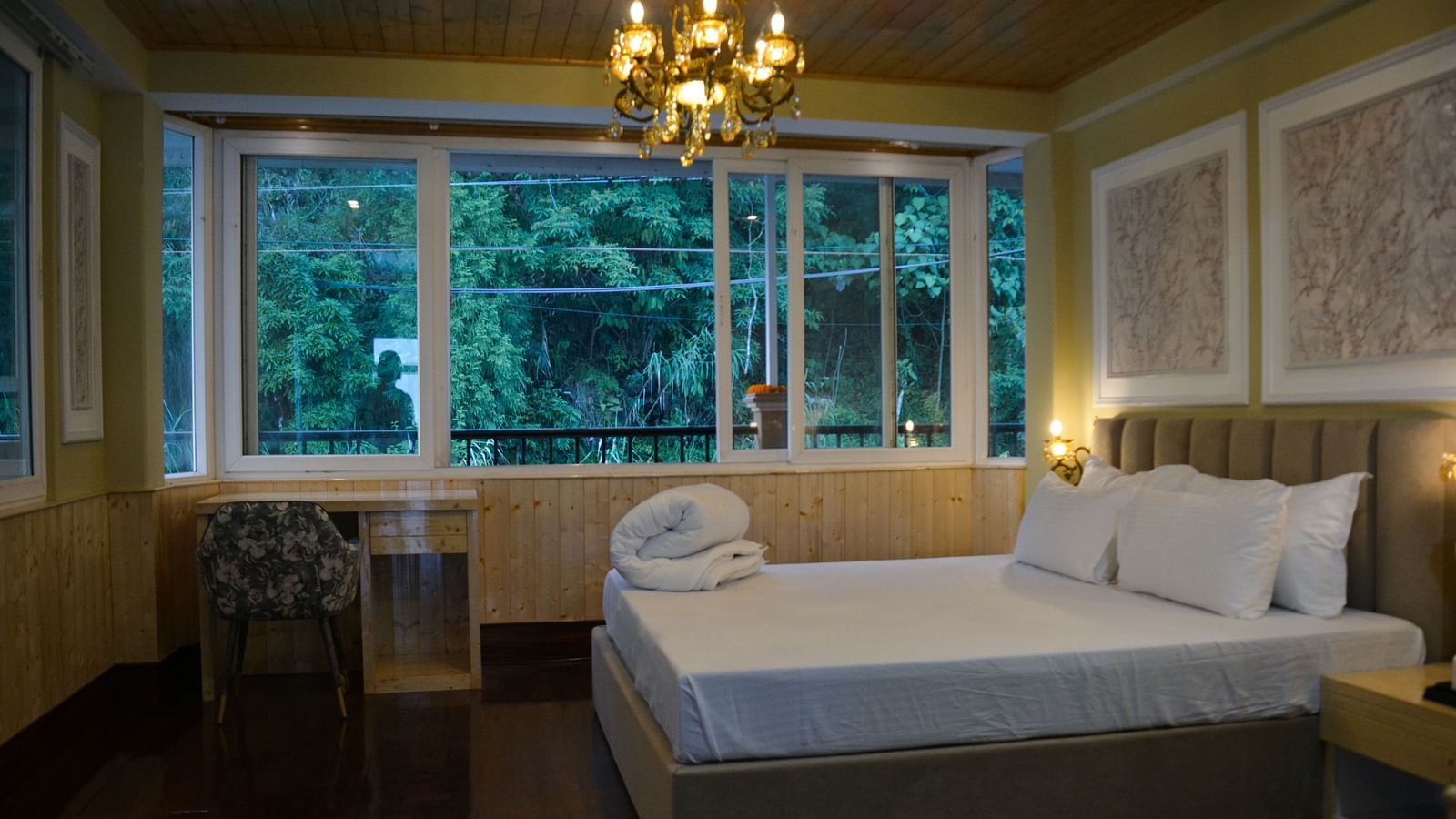 An image of a bedroom with king size bed with a side table with a chandelier and expansive window  - Avianna Windy House Wellness Retreat & Spa