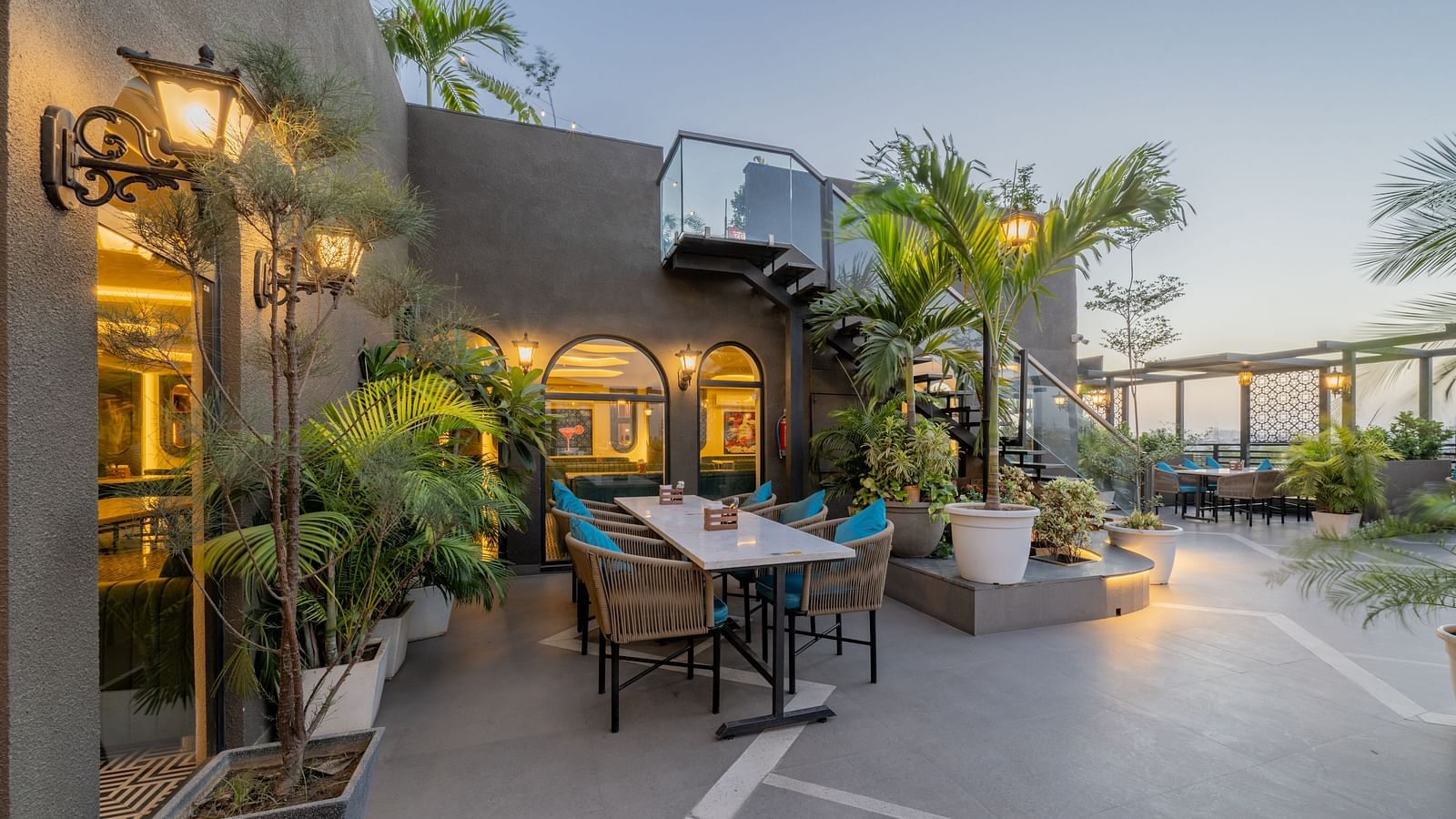 Cosy outdoor seating near arched window and tropical plants at Hotel Highway King, Jaipur.