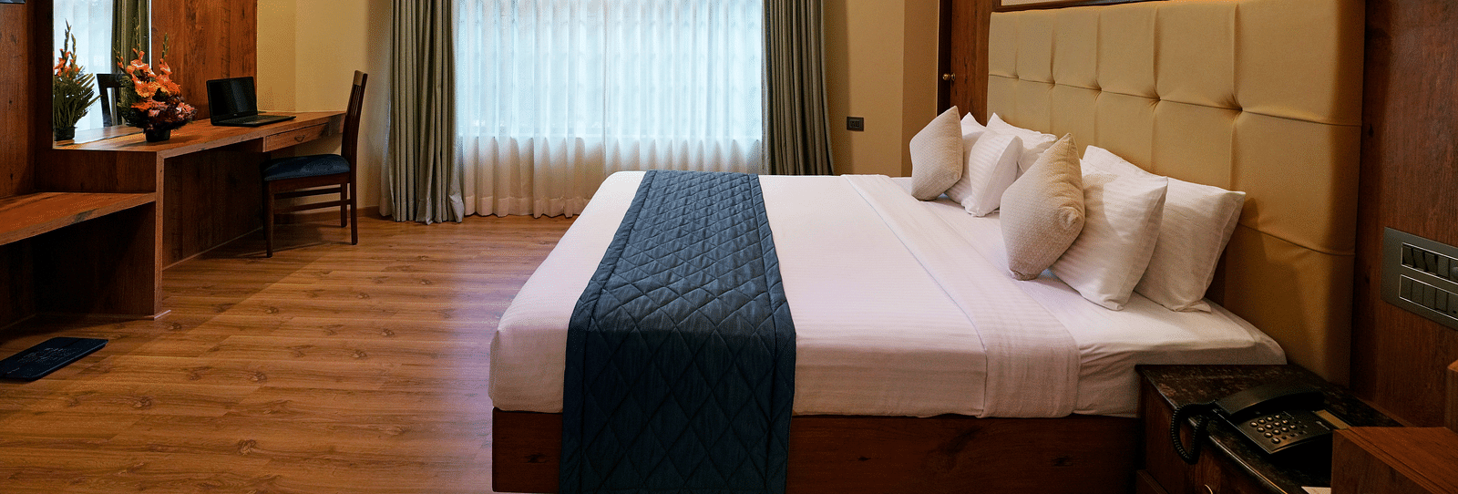 An Executive Room with a large bed, wooden decor, and natural light - Cross Roads Inn, Bengaluru