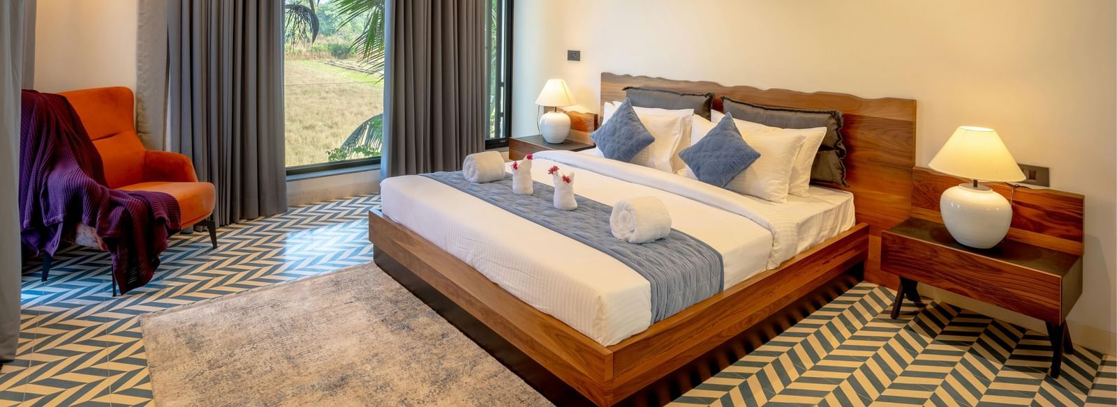 A cosy room featuring a neatly made bed, matching side tables, a large window that fills the space with natural light, and contemporary furnishings