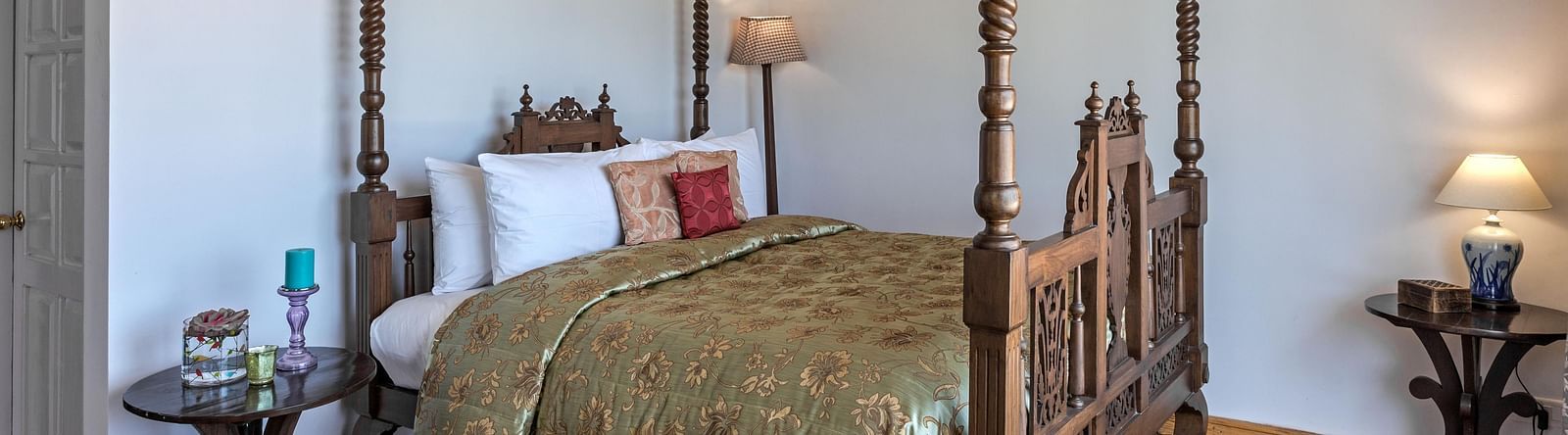 Side view of the  Superior Room  bed with wooden frames and lamp placed on the side of the room at Te Aroha by Shervani Mukteshwar