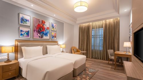 twins beds, a side table with a lamp, a work desk with a chair, and a television in one of the rooms at Park Plaza, Jalandhar