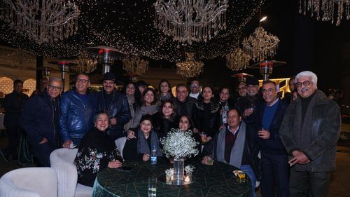 An image of people gathered around behind a table and below a chandelier light at Heritage Village Resorts & Spa