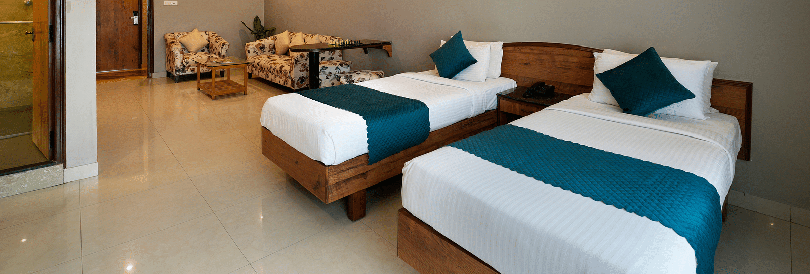 An image of an elegant Executive Room featuring twin beds and a seating area - Cross Roads Inn, Bengaluru