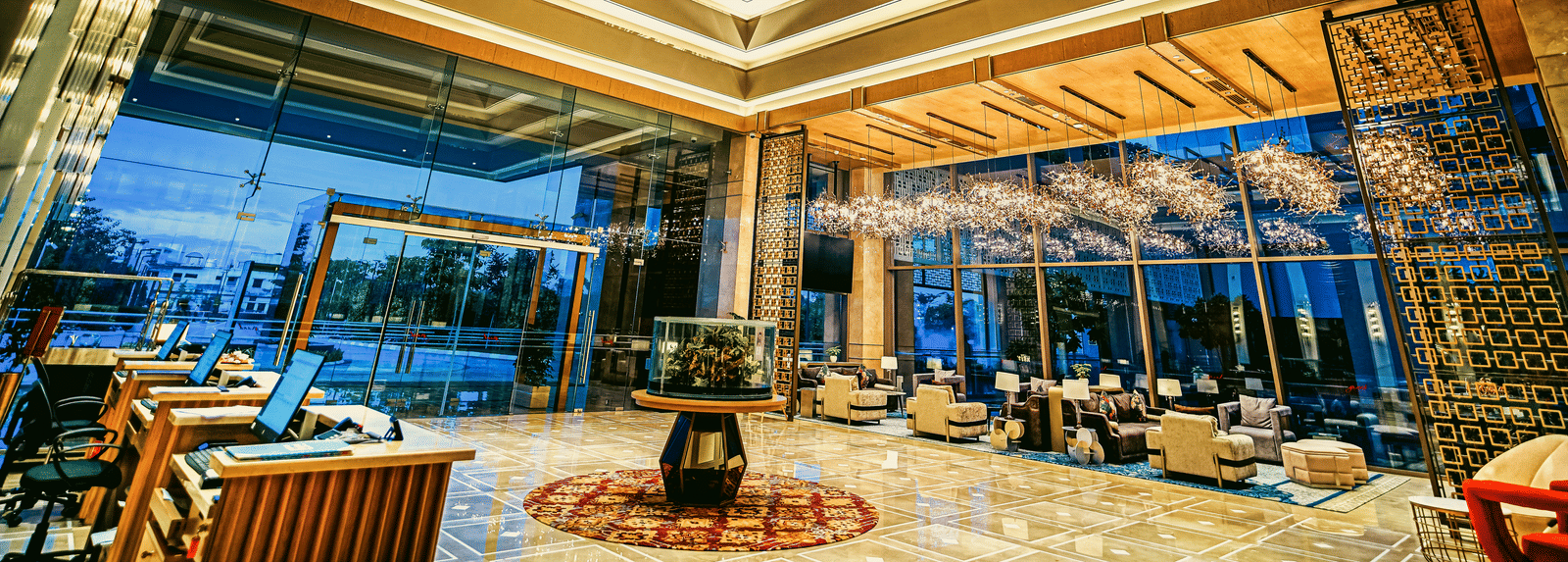 A grand hotel entrance with a central fountain, expansive windows, and elegant lighting - Grand Madurai by GRT Hotels