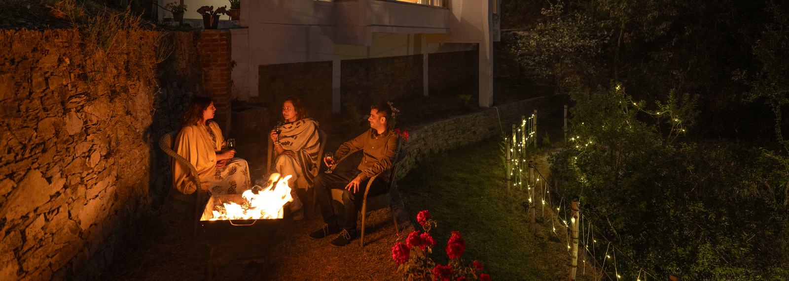 A group of people are sitting around a bonfire in front of a multi-story building at Ziran Retreat.