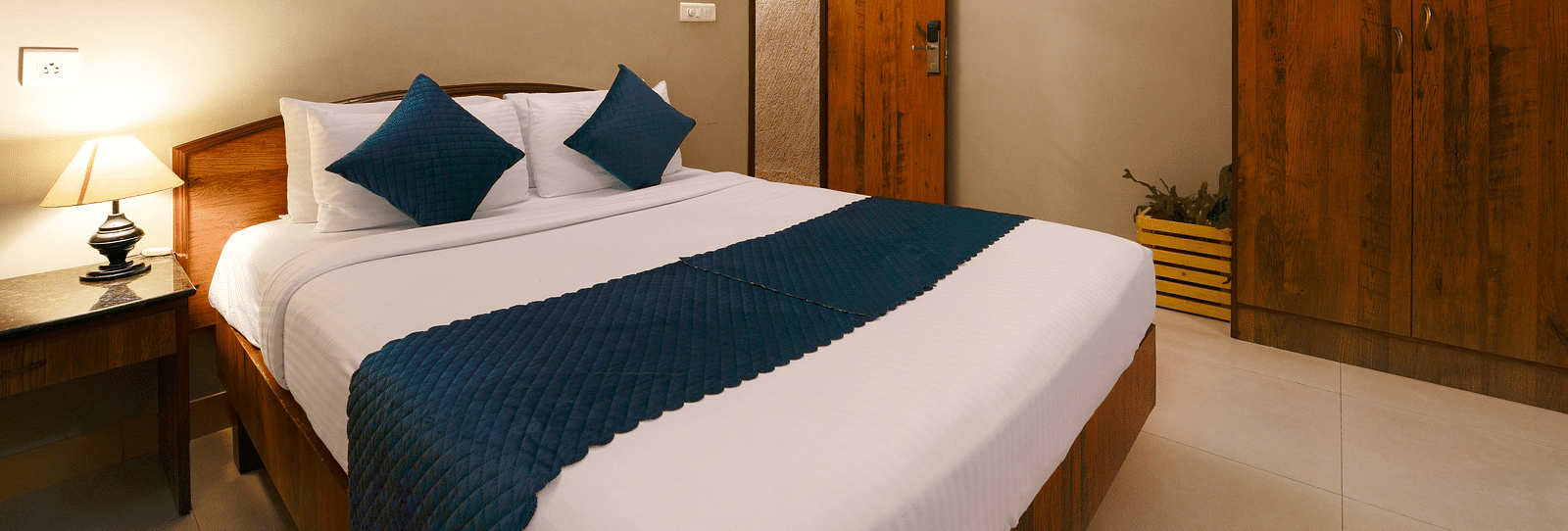 A Deluxe Room with a queen size bed, minimalist design, and modern amenities - Cross Roads Inn, Bengaluru