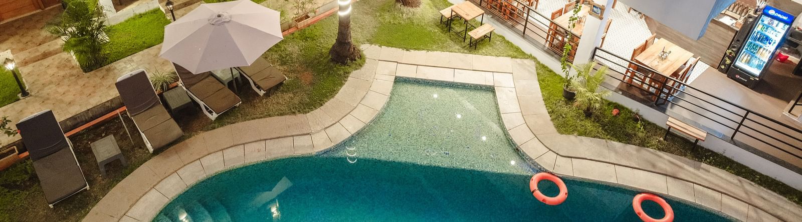 Aerial view of the swimming pool surrounded by sun loungers and palm trees at The Verda de Miranda Resort.