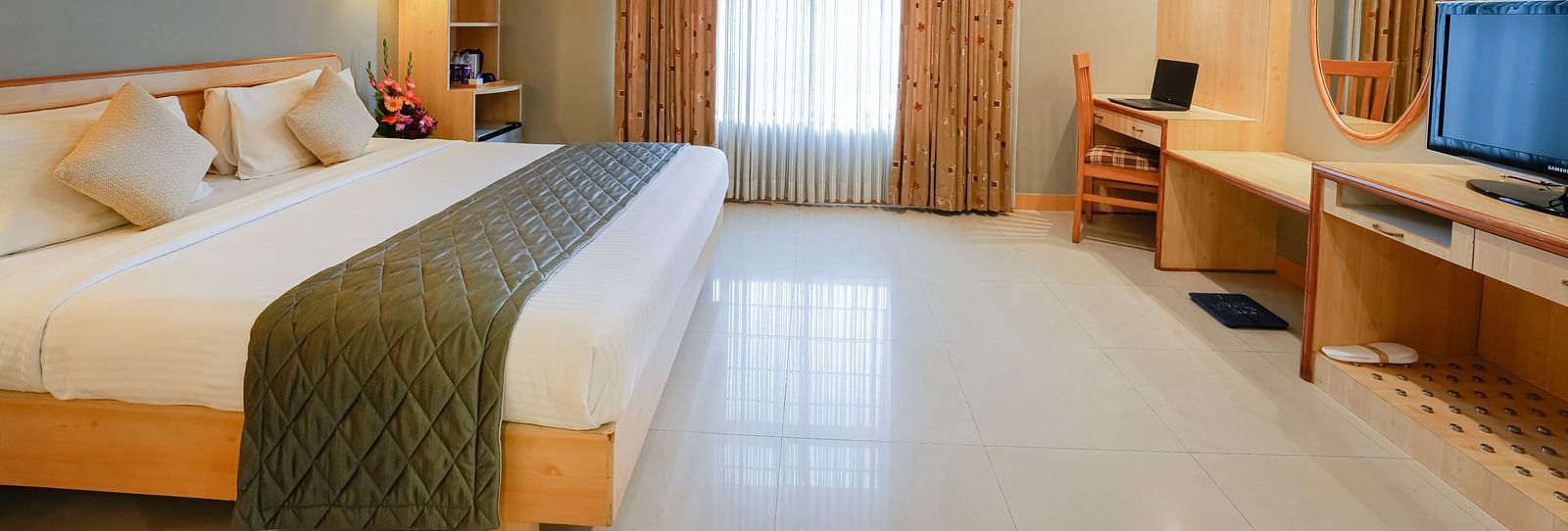An image of a Suite with plush bedding, a work desk, and ample natural light - Cross Roads Inn, Bengaluru