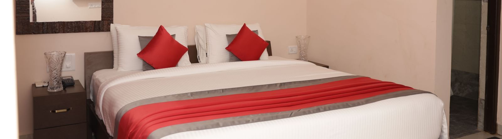 A bed with pillows, bedside tables, wall art and a mirror at Nazri The Verda Hotel, Arambol.