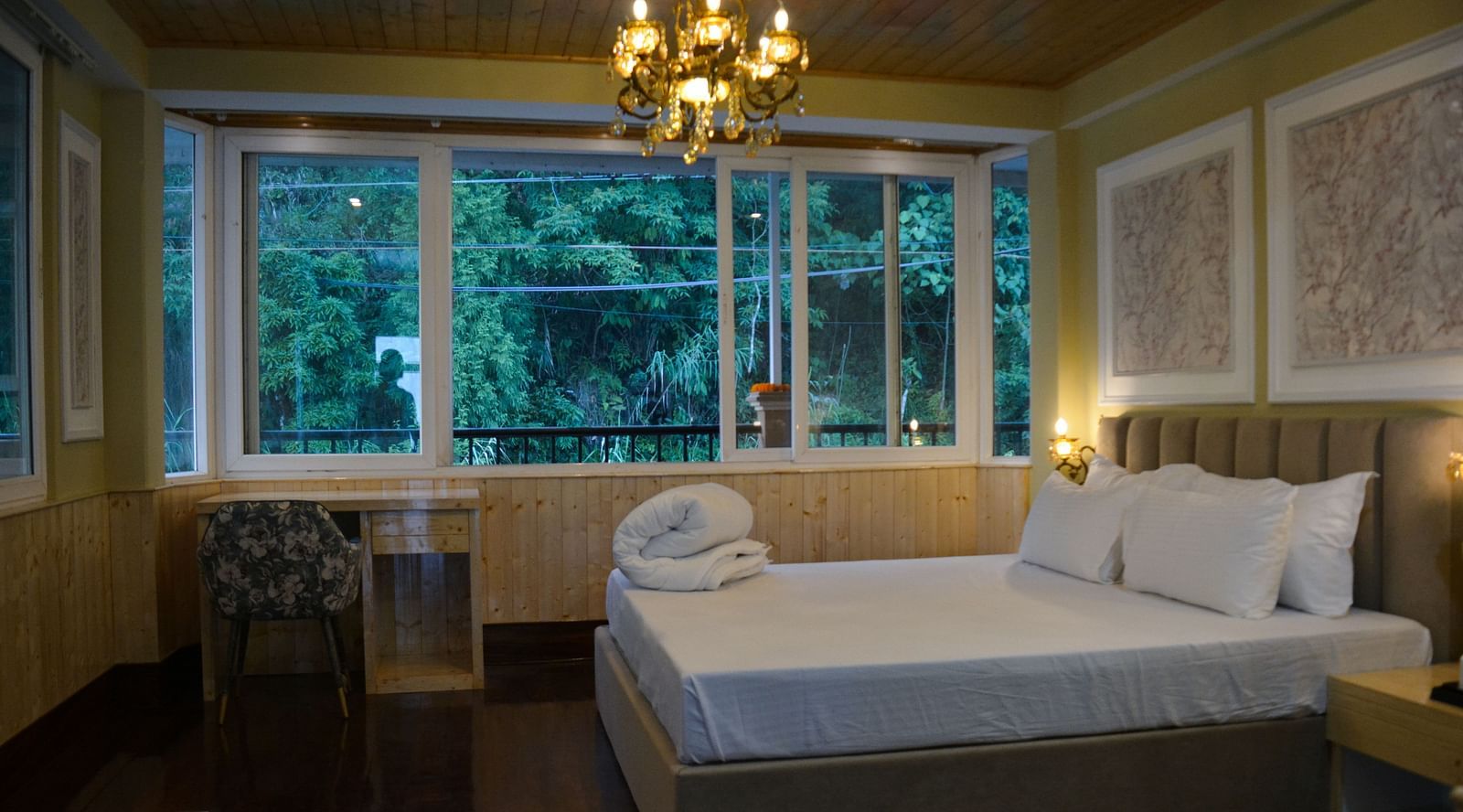 An image of a bedroom with king size bed with a side table with a chandelier and expansive window  - Avianna Windy House Wellness Retreat & Spa