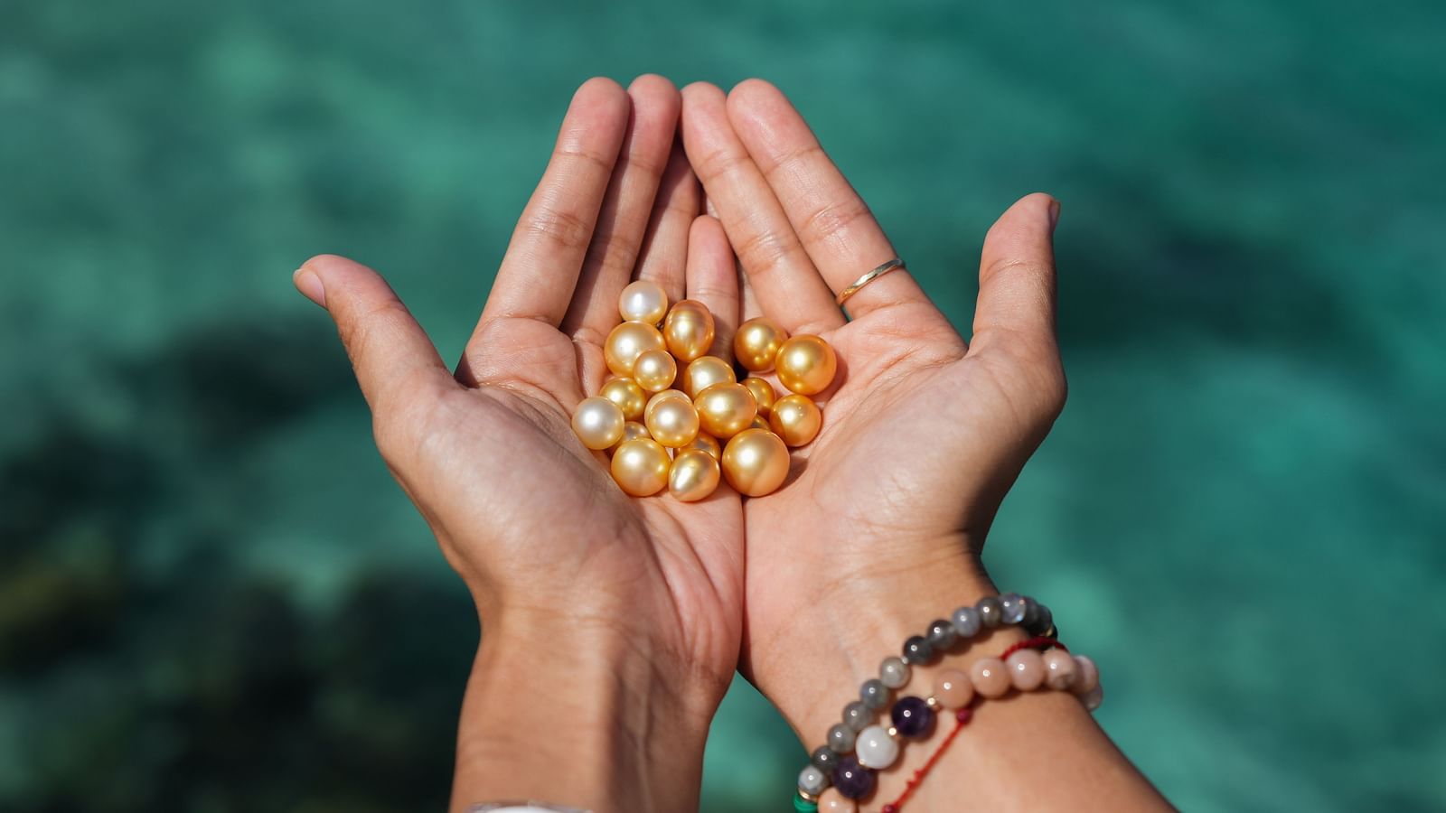 Hands holding a collection of yellow pearls at Flower Island Resort.