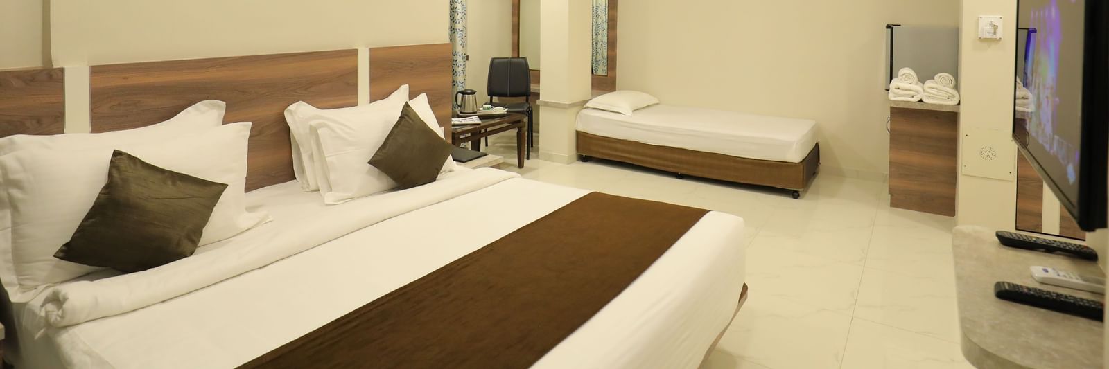 Close up of the king size bed and single bed in the Suite of Highland Resort, facing a wall-mounted TV.