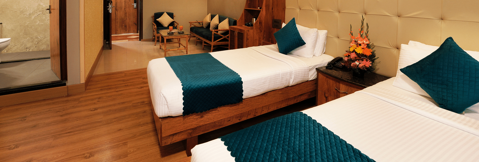  An Executive Room with cosy twin beds, a couch, and a glass-partitioned bathroom - Cross Roads Inn, Bengaluru