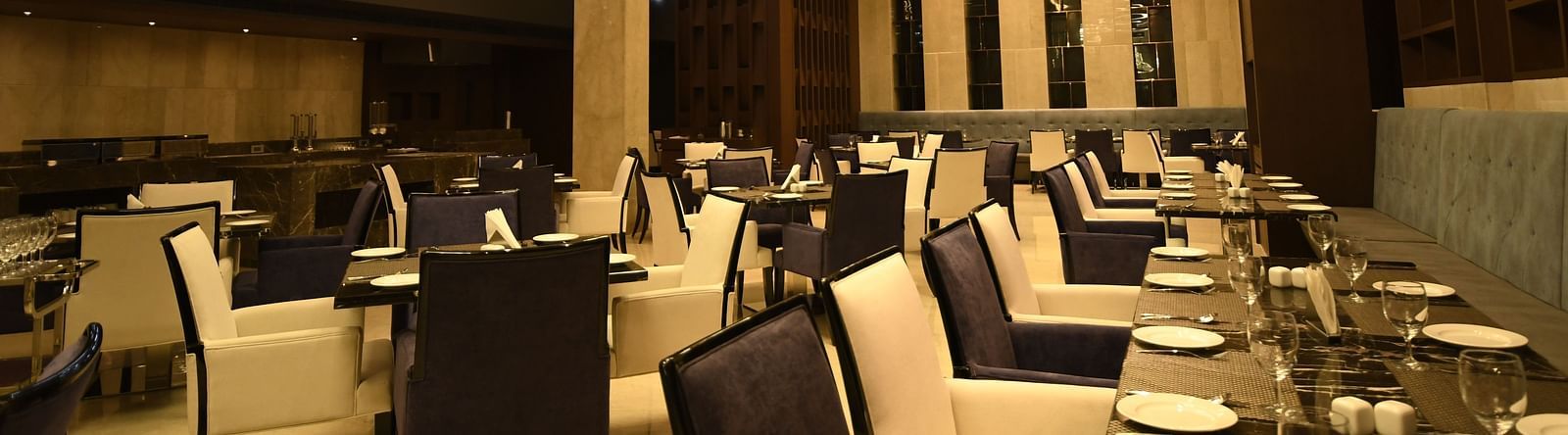  A dining area with cosy lighting, featuring tables set and chairs arranged for guests to savour their meal