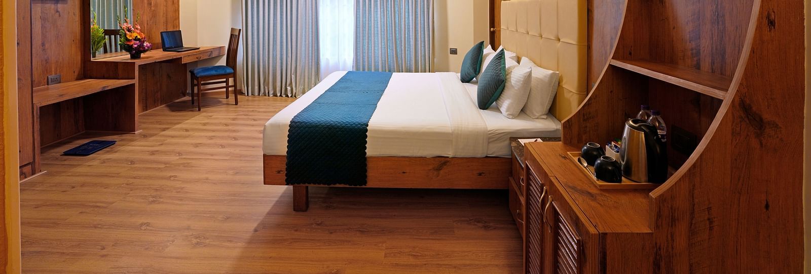 An Executive Room featuring a queen size bed, wooden decor and large windows - Cross Roads Inn, Bengaluru