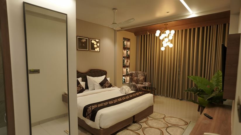 Suite Room at Pride Comfort, Dwarka with a double bed, a television and a chandelier.