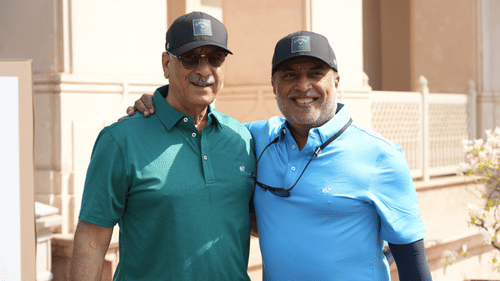 Two men in golf attire smiling and posing together at a corporate golf event.