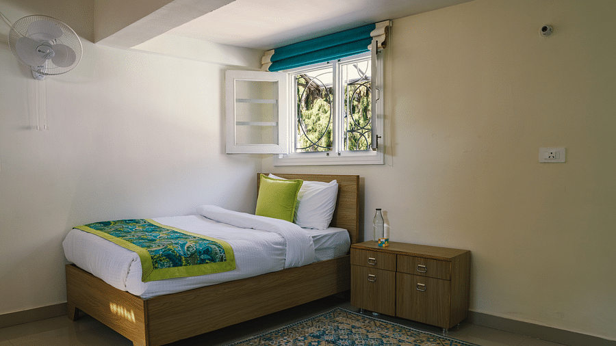 A spacious room with a single bed near the open window and a bedside table at BluSalzz Villas - The Green Roof, Bhimtal.