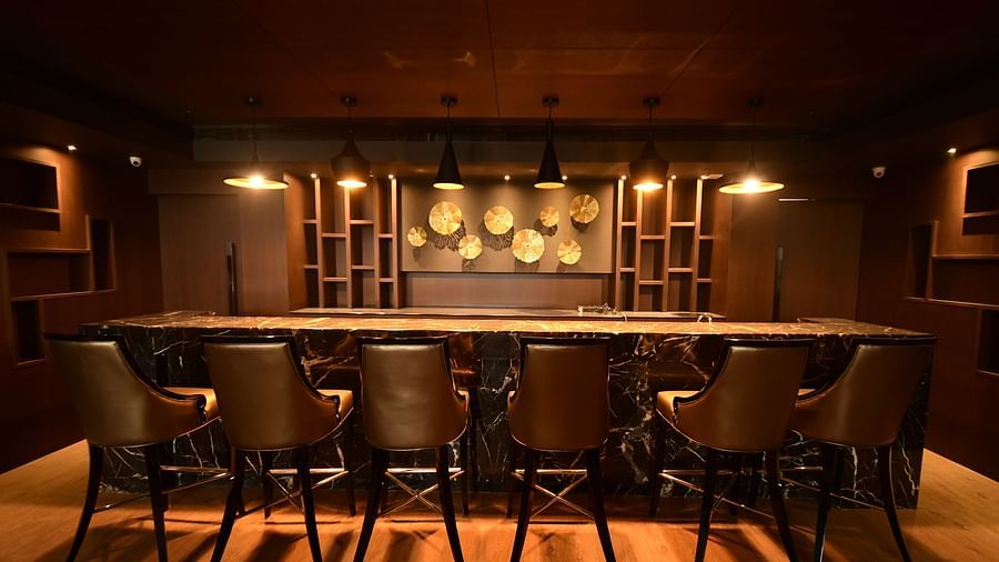 A back view of a large marble table surrounded by chairs, accented by warm lighting
