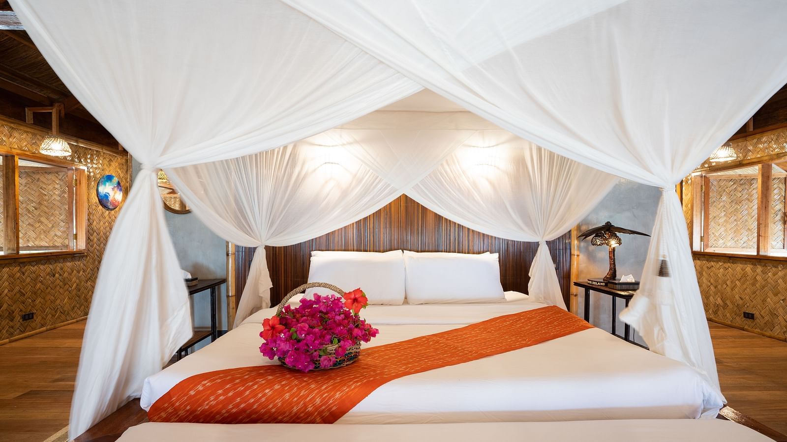 Close-up of a bed with white canopy netting and a folded towel with flowers on the bed at Flower Island Resort.