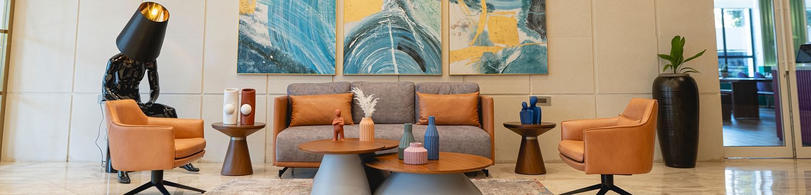 Lobby at KertelSuites, featuring a cosy sofa, a round coffee table, and an elegant ceiling with stylish lighting.