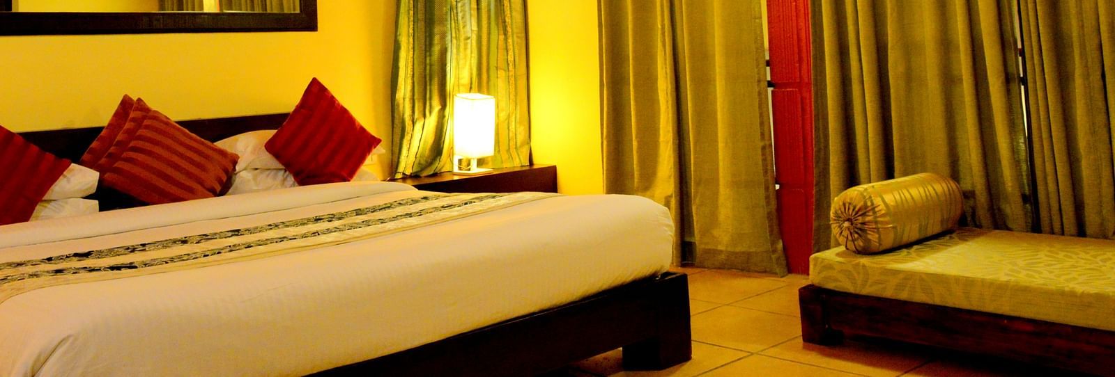 a bedroom with a bed and large curtains and a sofa on the side - Kadkani River Resort, Coorg