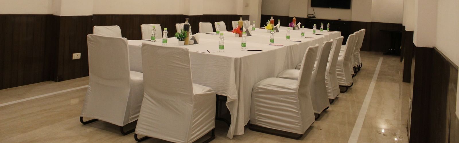 An image of a conference hall featuring a a large table at the centre surrounded by several chairs at Inde Hotels Vista Woods