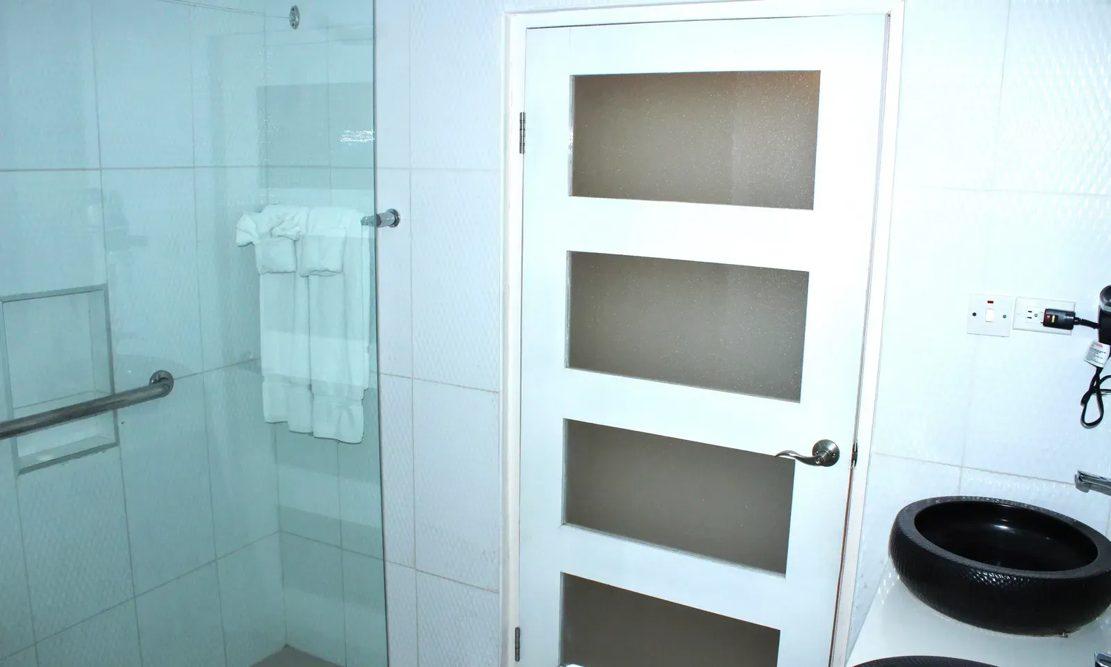A bathroom with a clear glass shower enclosure and a separate toilet area, featuring a modern design | Executive King Room | Altamont Court, Jamaica