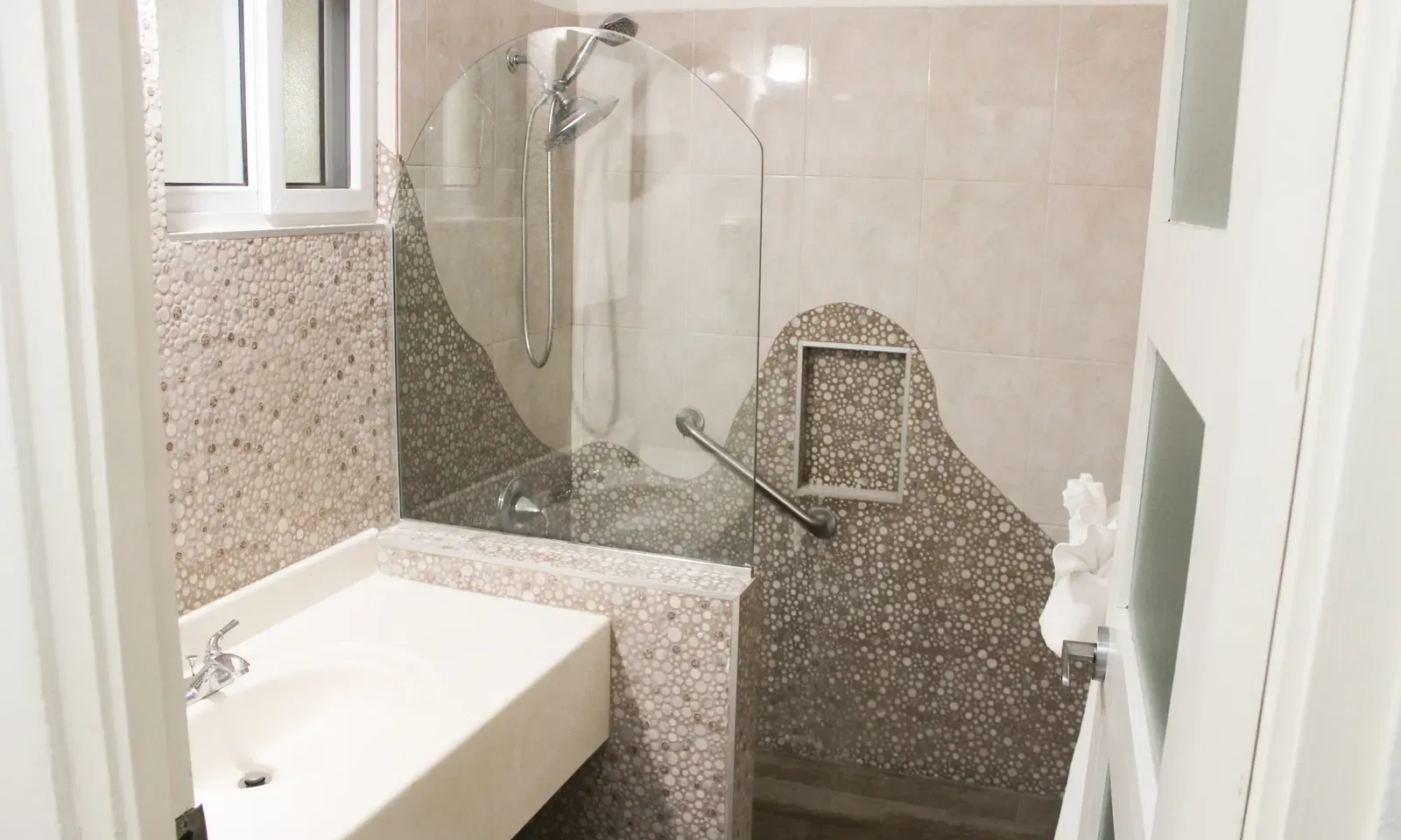 A modern bathroom features a shower stall with a glass door, a toilet, and a vanity with a sink | Executive King Room | Altamont Court, Jamaica