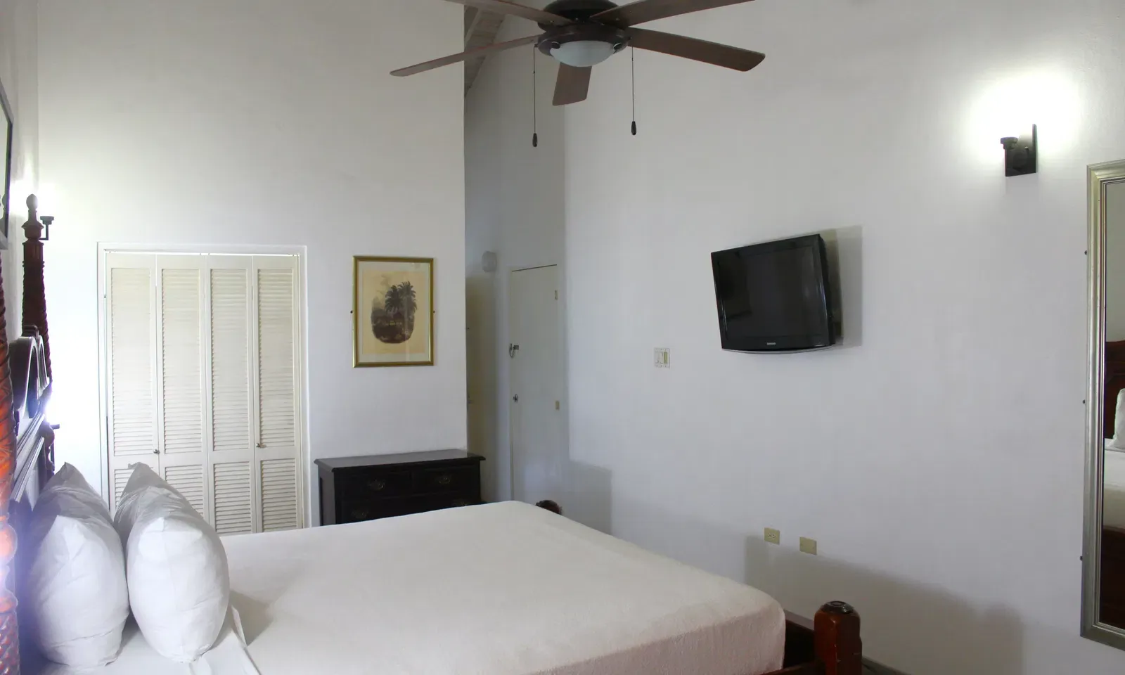 A hotel room with a single bed, a ceiling fan, and a wall-mounted television | Executive King Room | Altamont Court, Jamaica