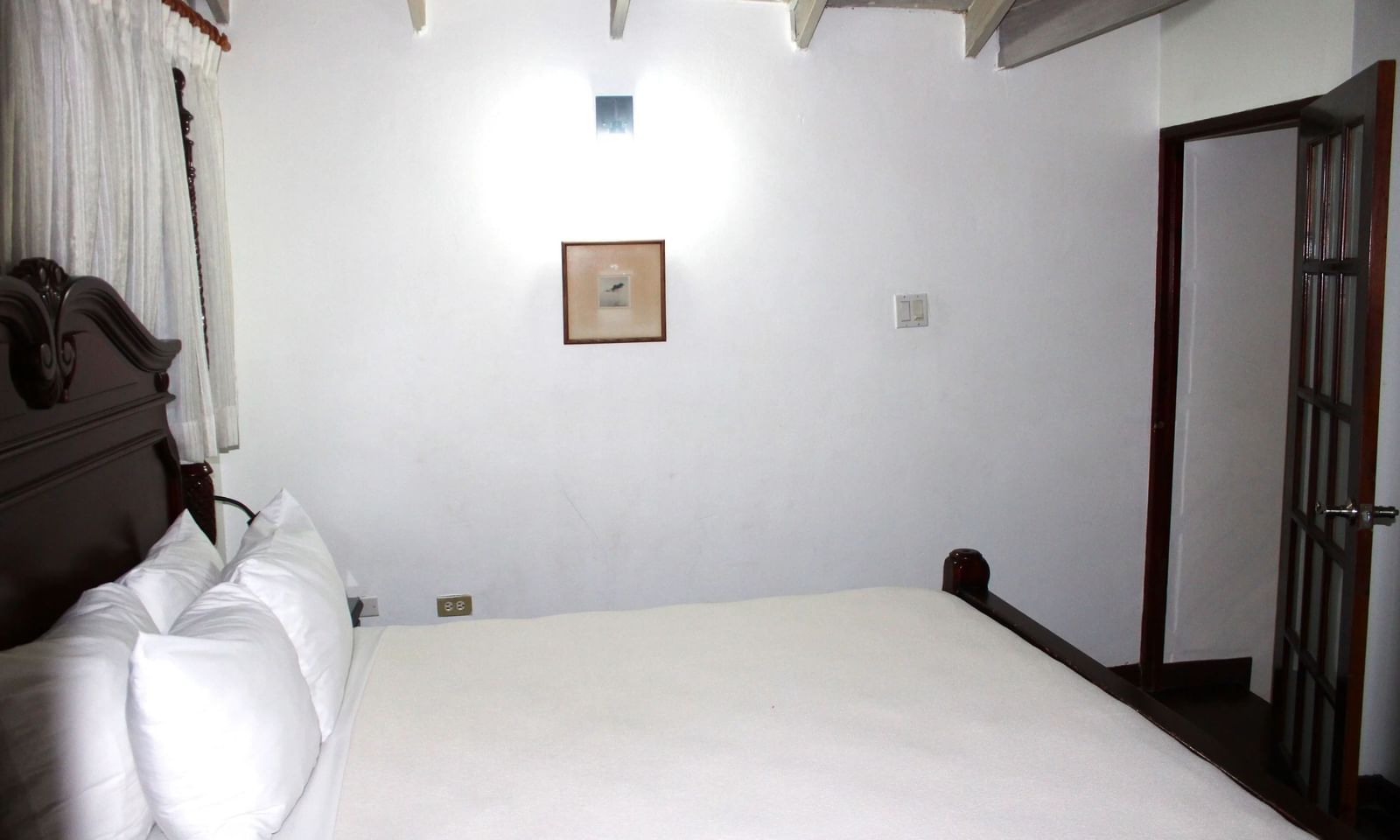 A minimalist white room with a bed on the floor and a single light fixture | Superior Suite | Altamont Court, Jamaica