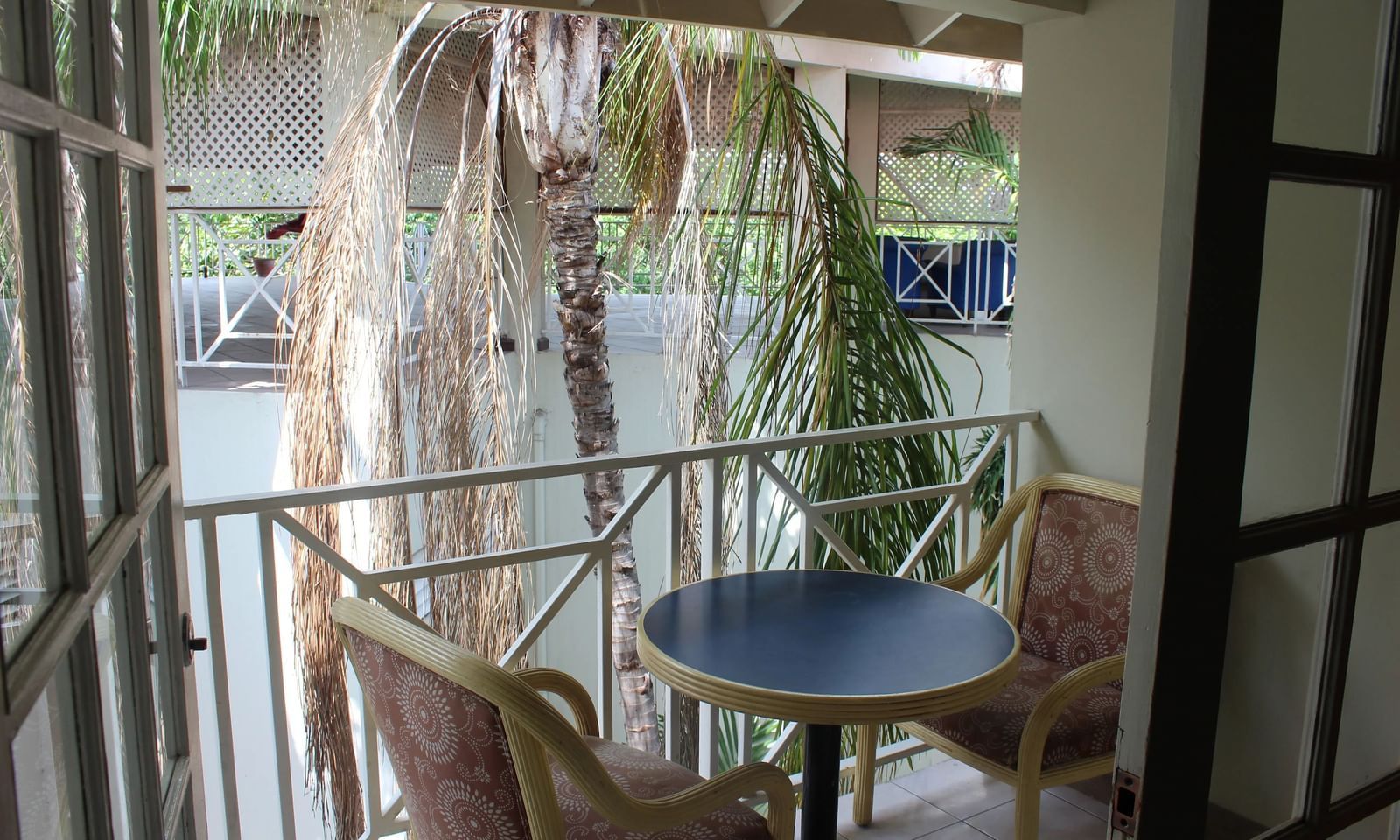 An outdoor balcony or patio area with a small table and chairs, enclosed by railings and surrounded by greenery | Junior Suite | Altamont Court, Jamaica