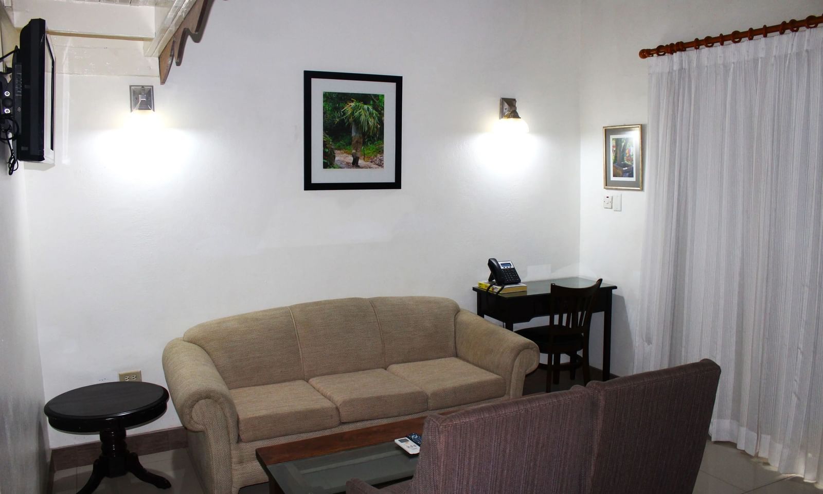 A living area with a light-colored sofa, dark furniture, and framed art on the wall | Superior Suite | Altamont Court, Jamaica