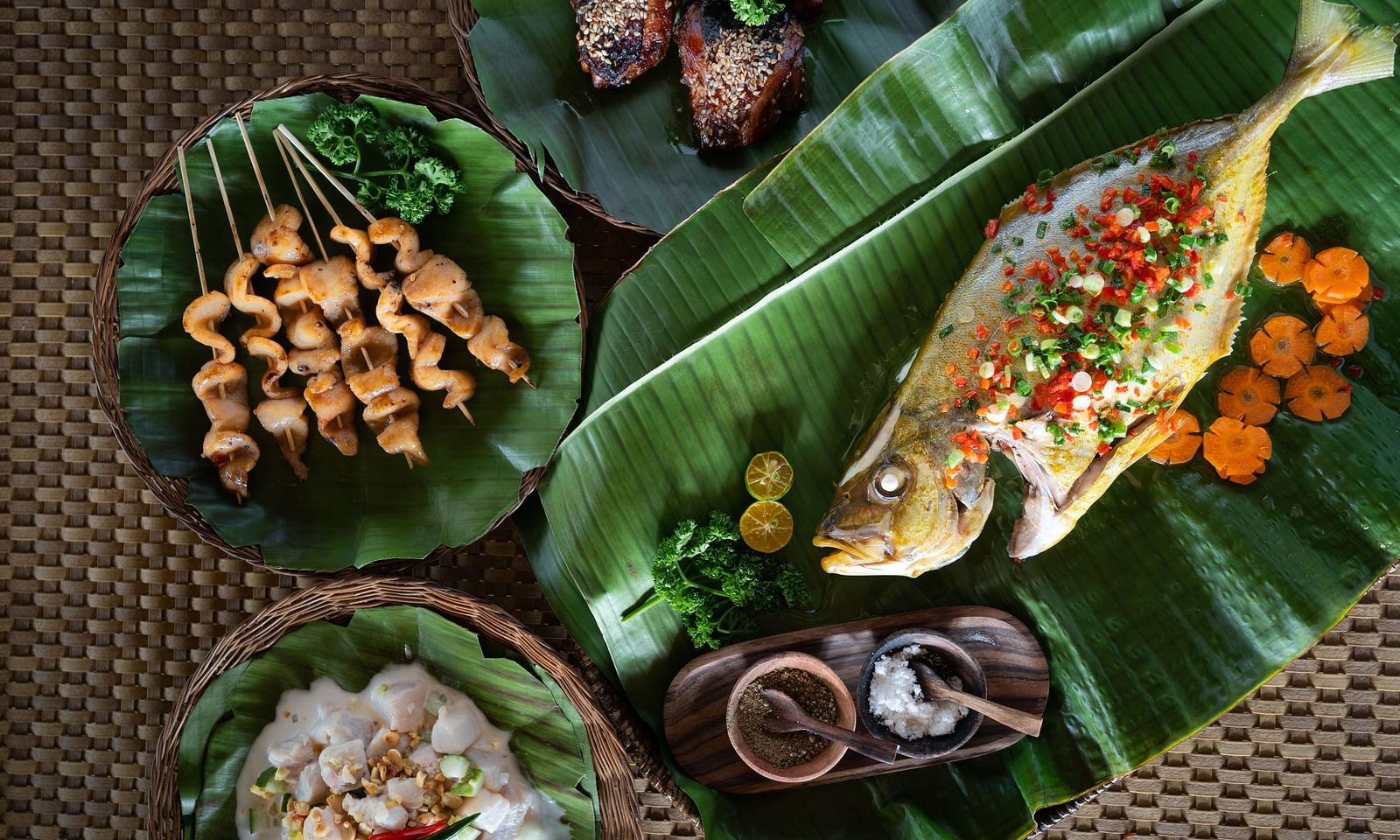 Traditional meal served on banana leaves with seafood, vegetables, and condiments at Flower Island Resort.