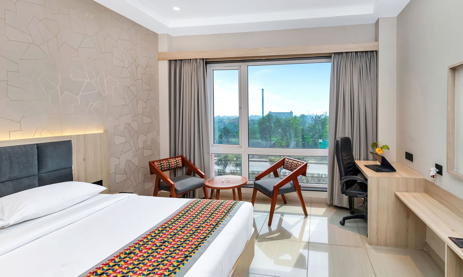 A bright hotel room with a bed, seating area, and work desk by a window | The Citi Residenci Hotel Banskopa