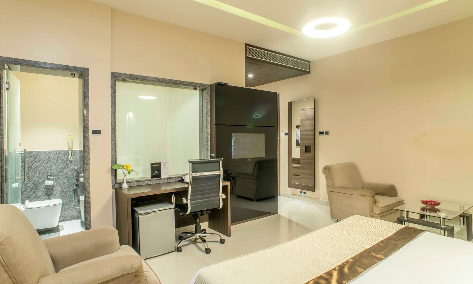 Modern hotel suite with a king size bed, a separate living area, and a glass-enclosed bathroom | The Citi Residenci Hotel Durgapur