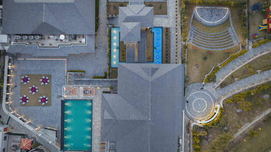 Bird's-eye view of Royal Tulip Shivapuri National Park - Kathmandu showing the swimming pool, rooftops, stone walkways, and outdoor courtyard.