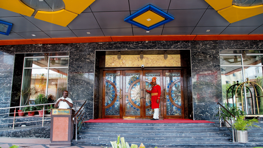 Entrance of Benzz Park, Vellore, featuring a doorman wearing a red coat ready to open the door for the guest.