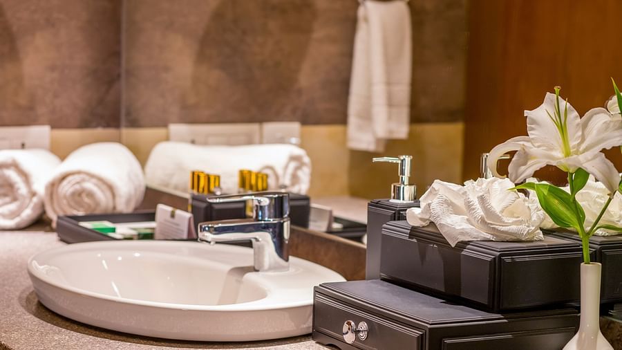  A selection of toiletries and towels neatly organised near the washbasin, with a vase of decorative flowers nearby.