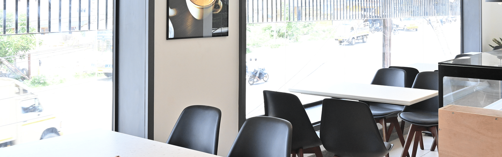 Side view of a coffee shop with chairs and lights hanging from the ceiling at Hotel Raai