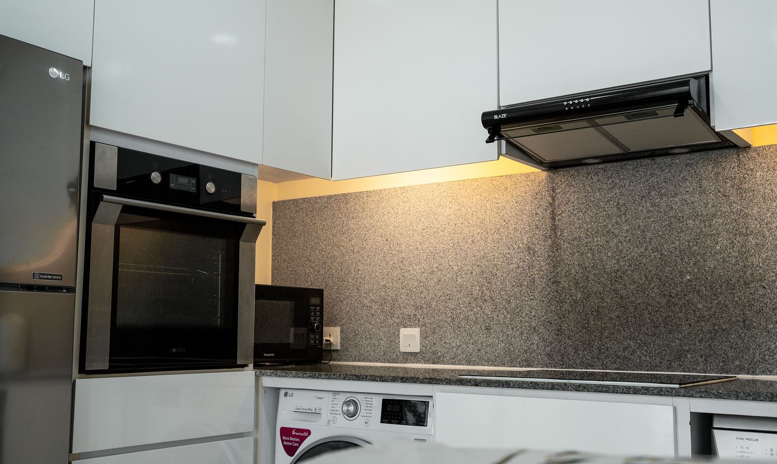 A modern kitchen with white cabinets, dark countertops, and stainless steel appliances | Four-bedroom Suite | Central Mansions, Phnom Penh