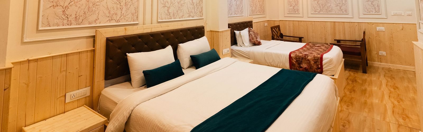 an image of a family room with two beds and two chairs at Avianna New Mandala Hotel & Spa, Darjeeling.