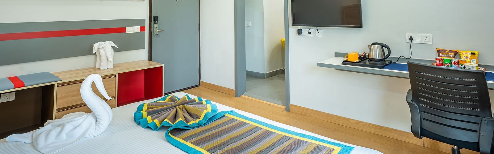 An image of a bedroom with chair, table, and a TV | Inde Hotel Golf Course Extension
