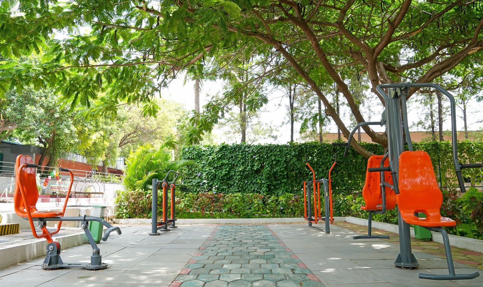 An outdoor fitness area with various exercise equipment under the shade of trees at Greens Inn - Outdoor Fitness Facilities in Ramoji Film City.