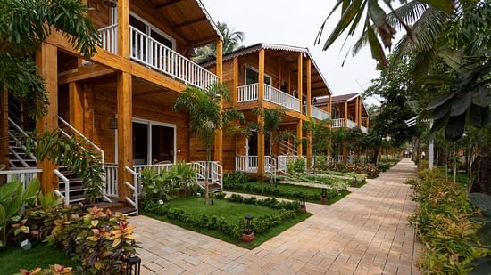 view of the resort pathway flanked by two-story wooden cabins with balconies and tropical plants - Aralea Beach Resort by Stone Wood, Morjim