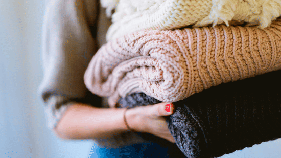 Person holding a stack of folded knitted fabrics
