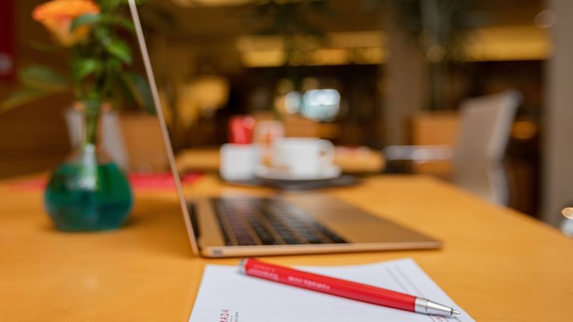 A workspace with a laptop, notepad, and a flower vase at Ramada Addis Ababa.
