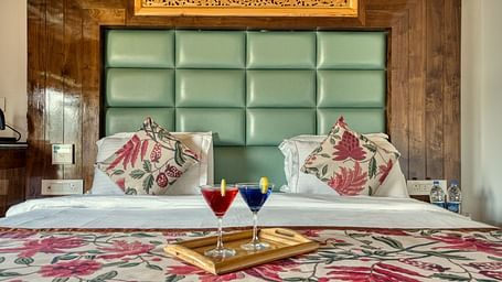 King size bed with floral bedding and welcome drinks at Royal Comfort Regency, perfect for a relaxing and stylish getaway.