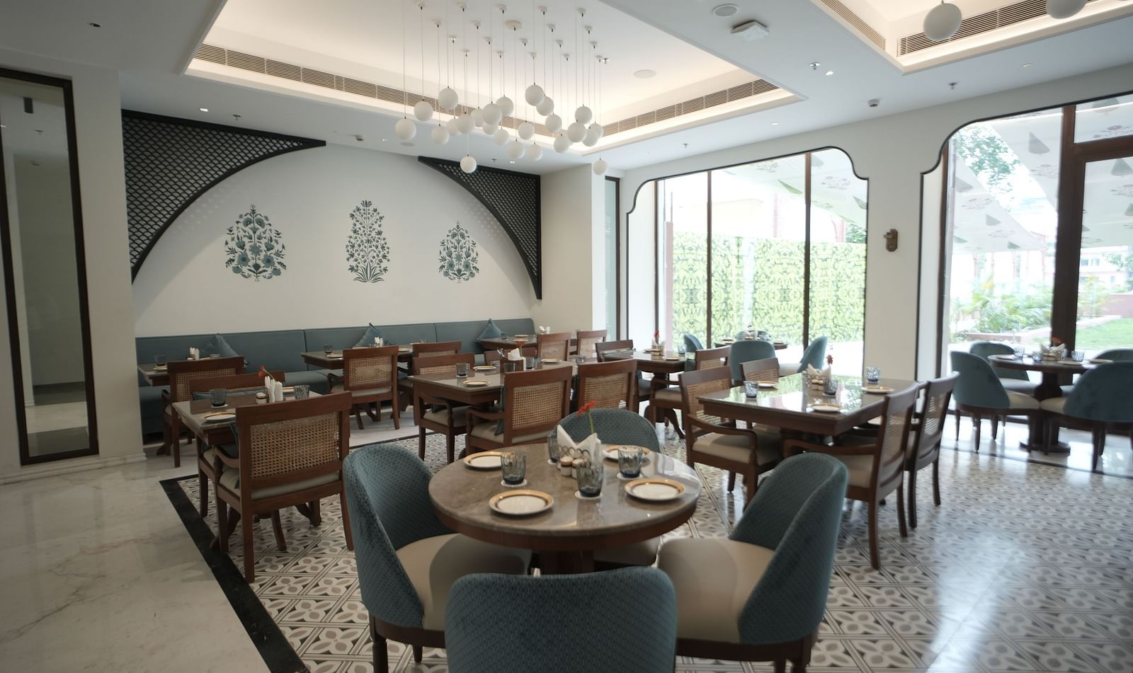 A brightly lit dining area with ample of natural lighting coming from the huge windows in the corner at Bhagirathi by RDB Atishay.